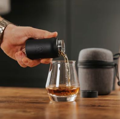 Pouring drink into glass on table.