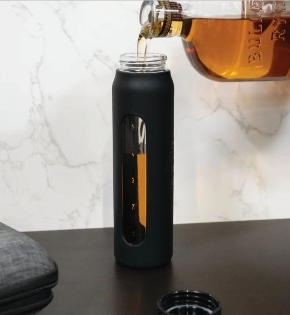 Pouring liquid into black bottle with window.