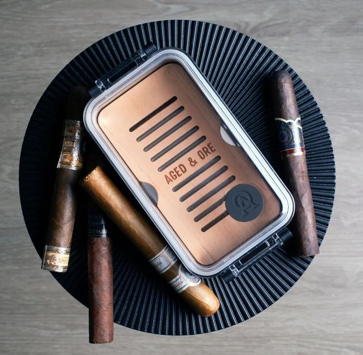 Cigars and wooden humidor on round table.